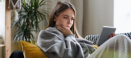woman on couch with blanket and tablet