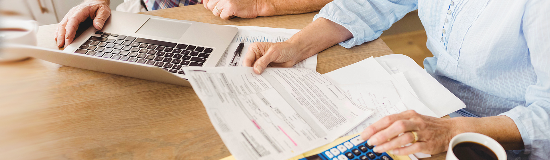 elderly couple looking at bills with laptop and calculator